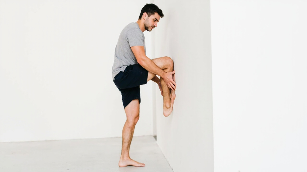 Person performing calf stretch at bedside with leg extended on bed